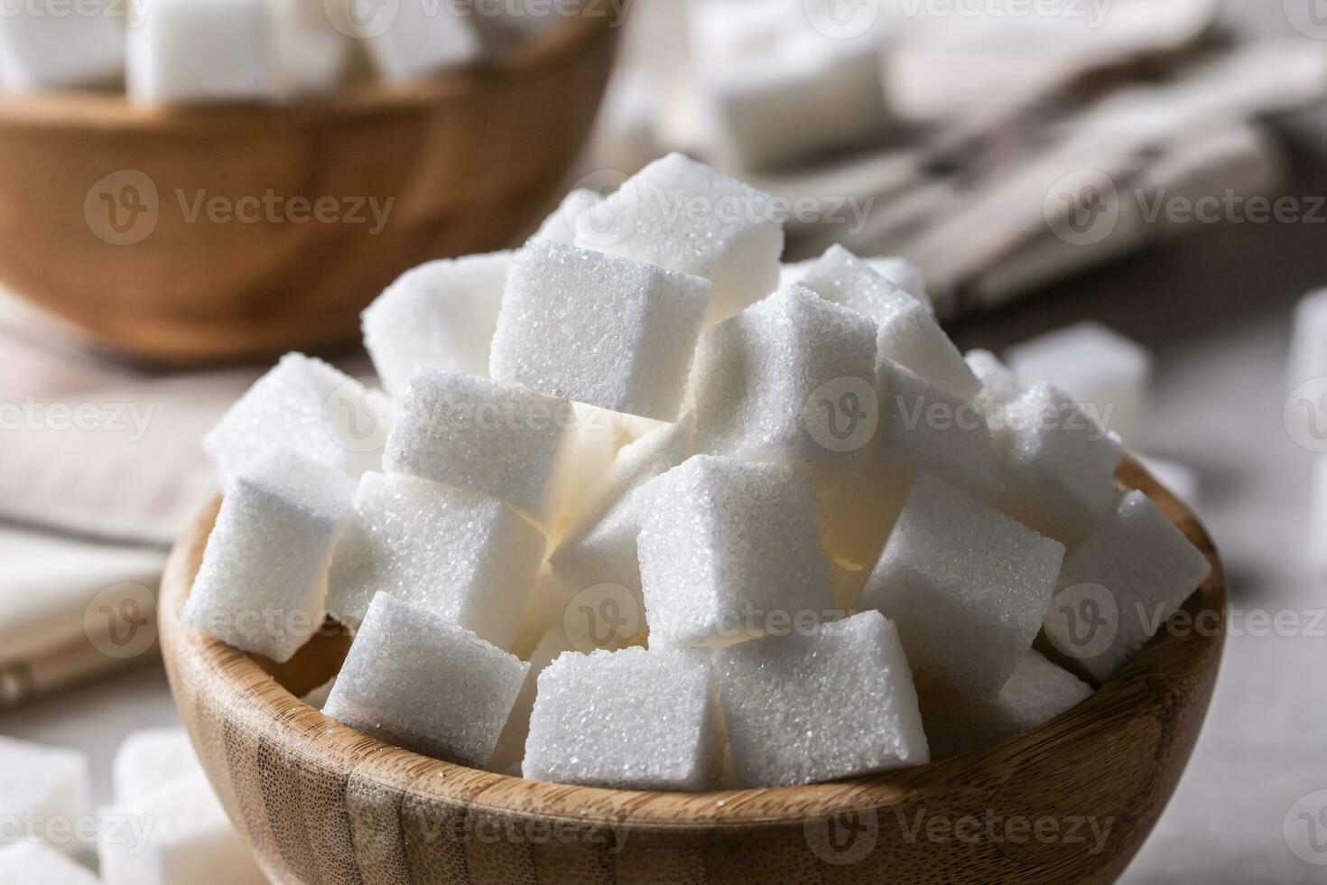 blanco azúcar cubitos en un de madera cuenco en el mesa foto