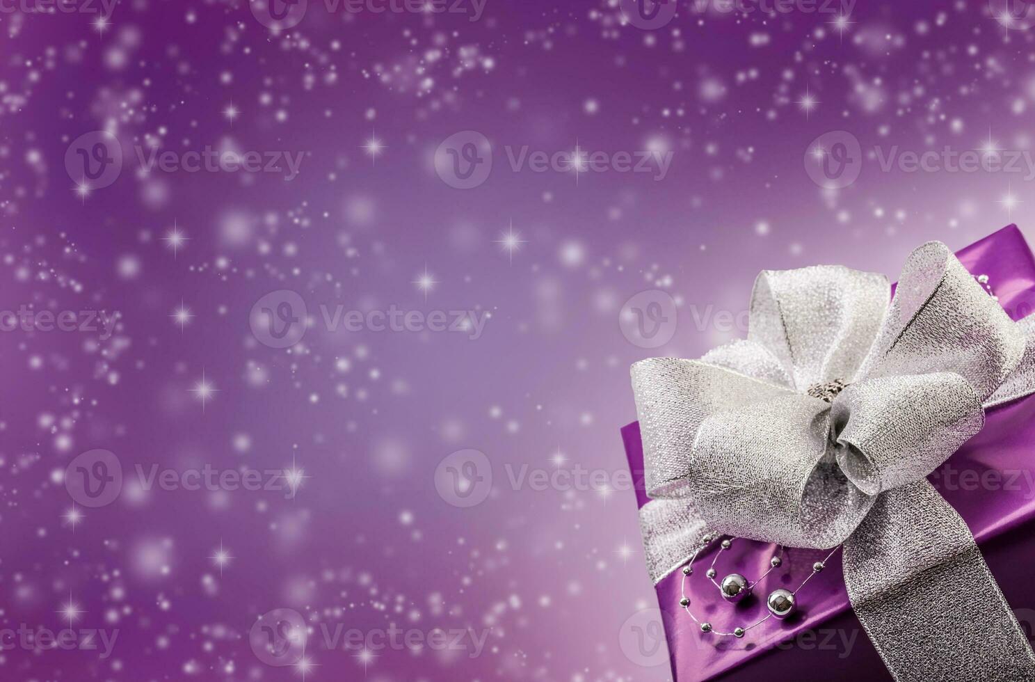 Christmas bokeh concept with purple present in the bottom right corner and illustrated snowflakes in the background photo