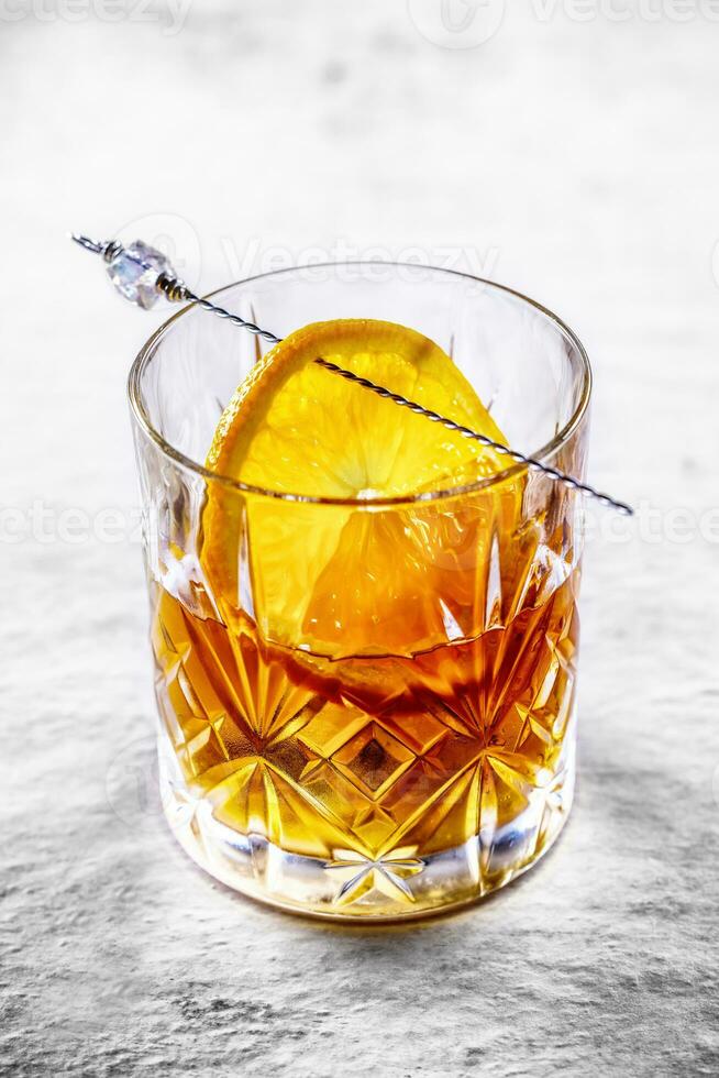 Old fashioned cocktail on a stoneware table - close up. Drink from whiskey, bourbon or rum photo
