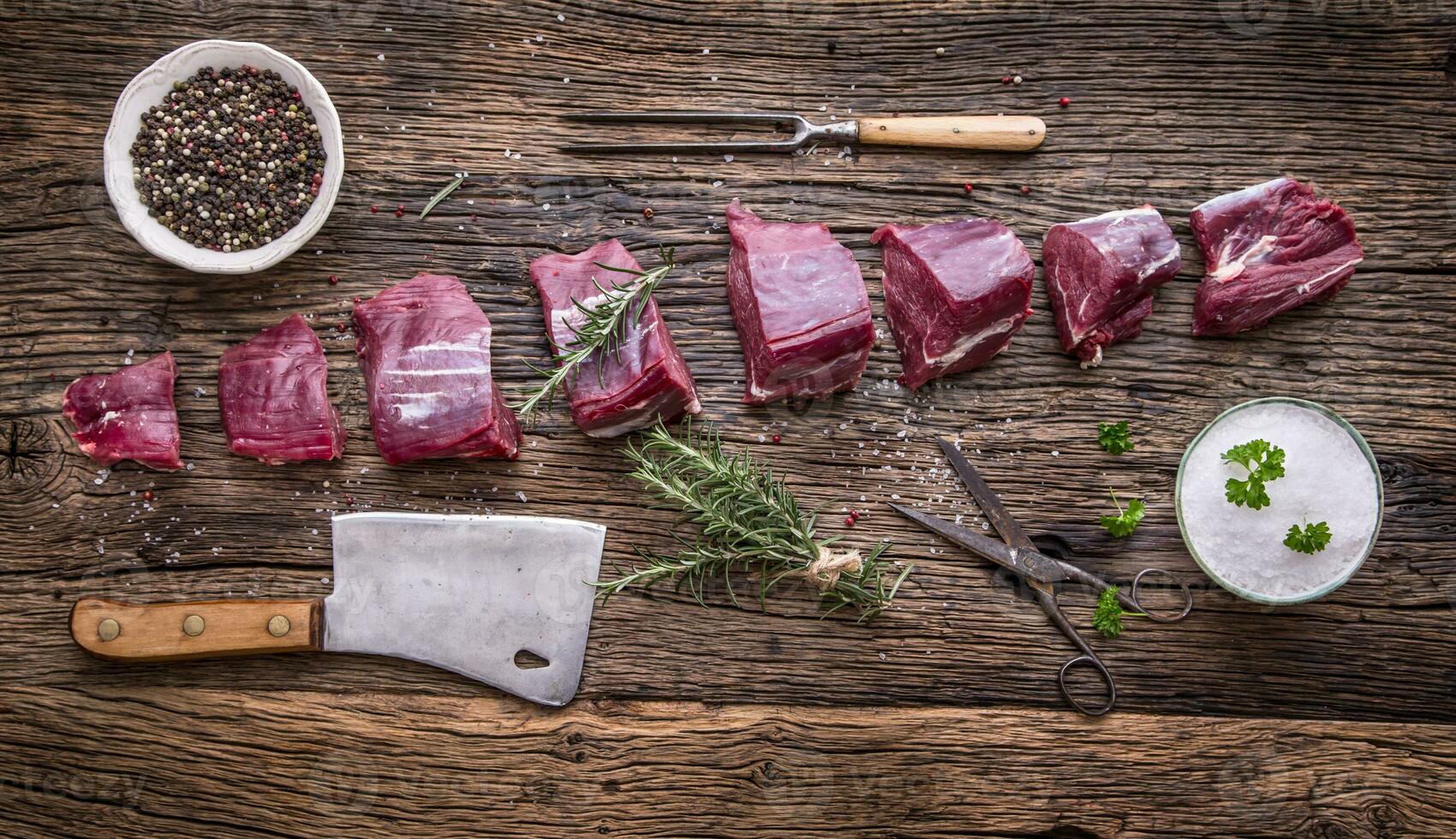 Raw beef steak in grill pan with salt pepper garlic and herbs on wooden table photo