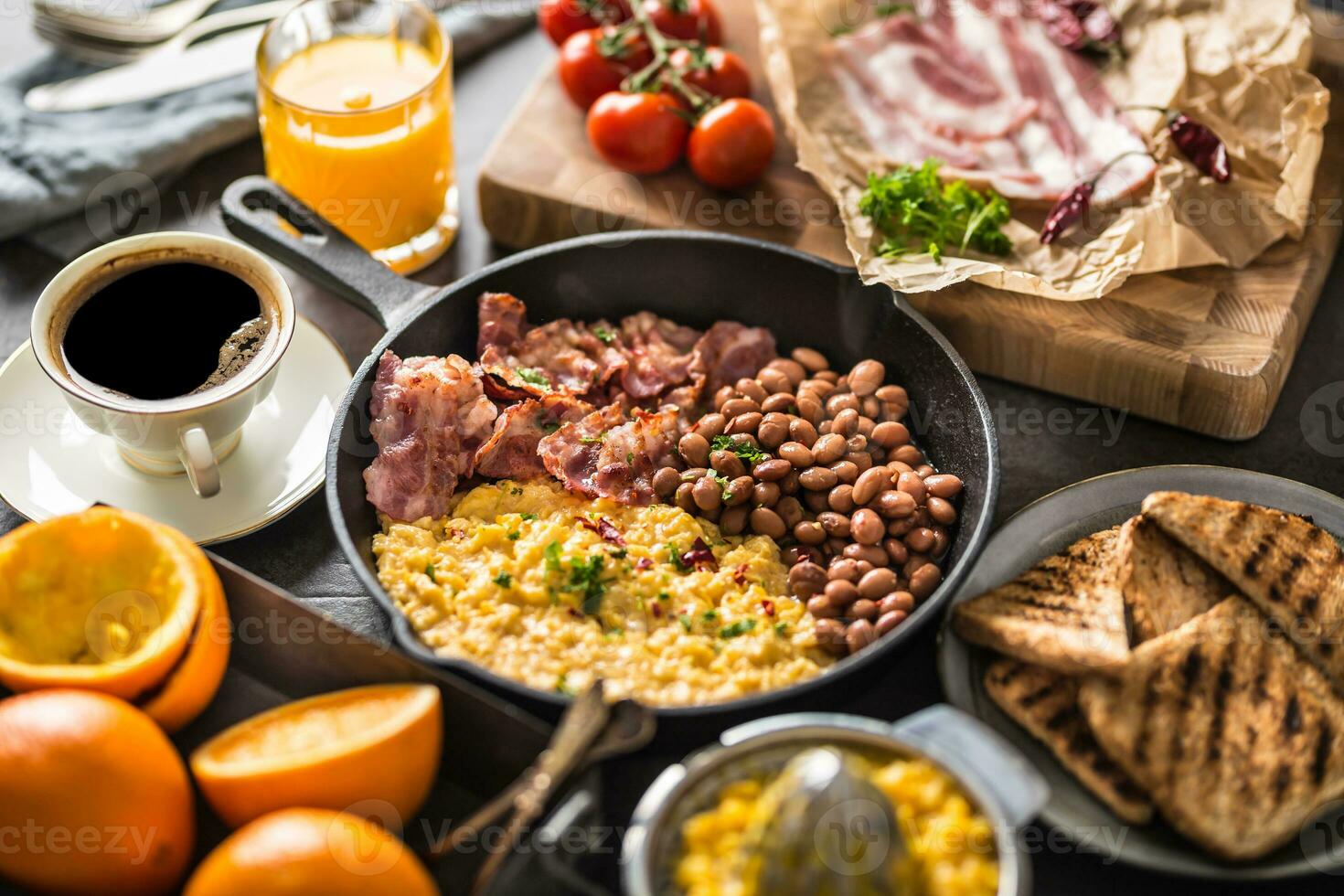 Full table of english breakfast. Scrambled eggs grilled bacon beans toast bread orange juice and coffee photo