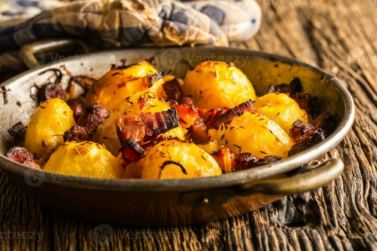 papas. asado patatas con tocino cebolla y salchichas en antiguo roble mesa foto