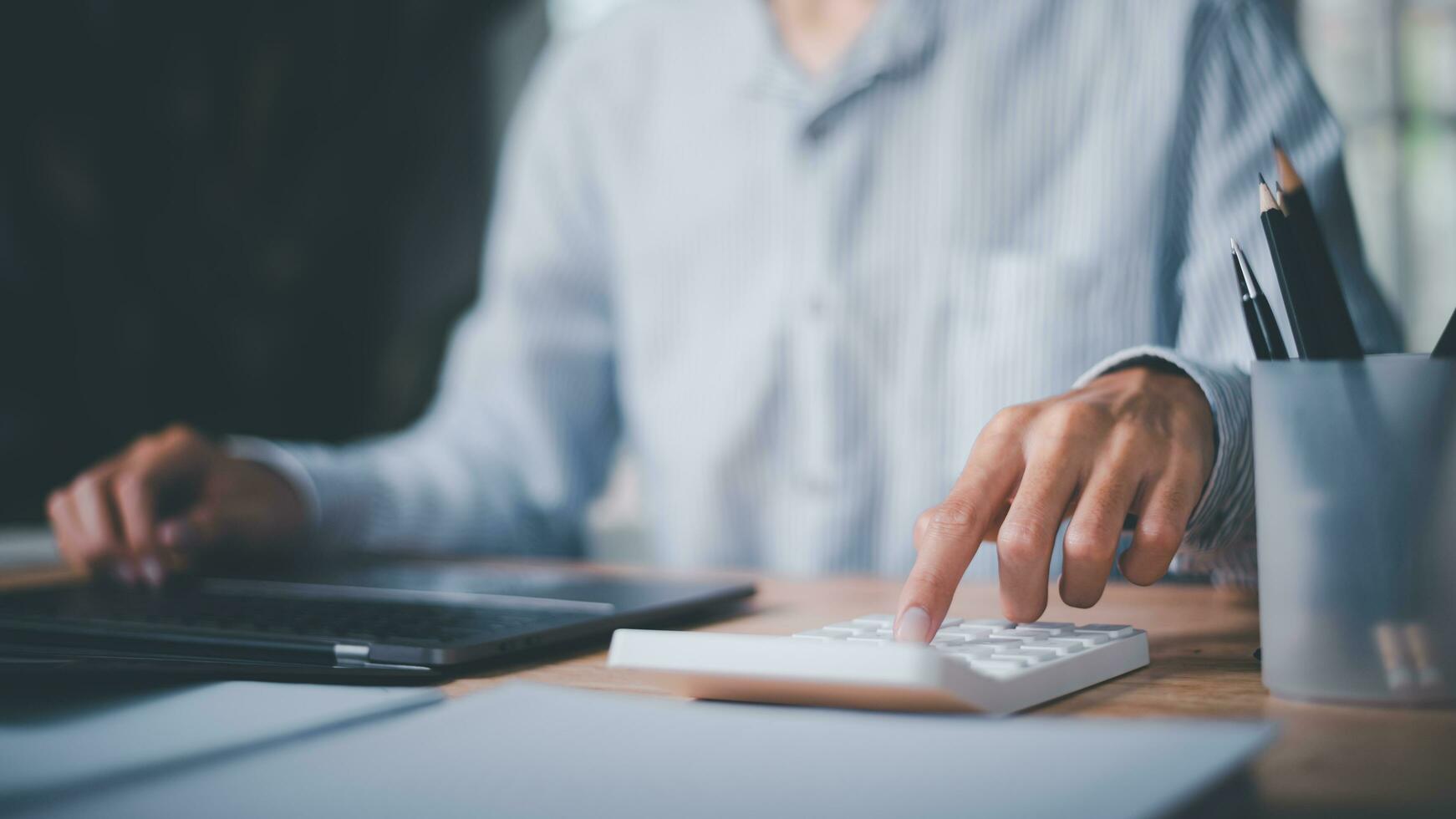 Businessman using calculator to calculate numbers ,profit and loss statement review of company performance ,Cost analysis and calculation of financial documents ,business account checking photo