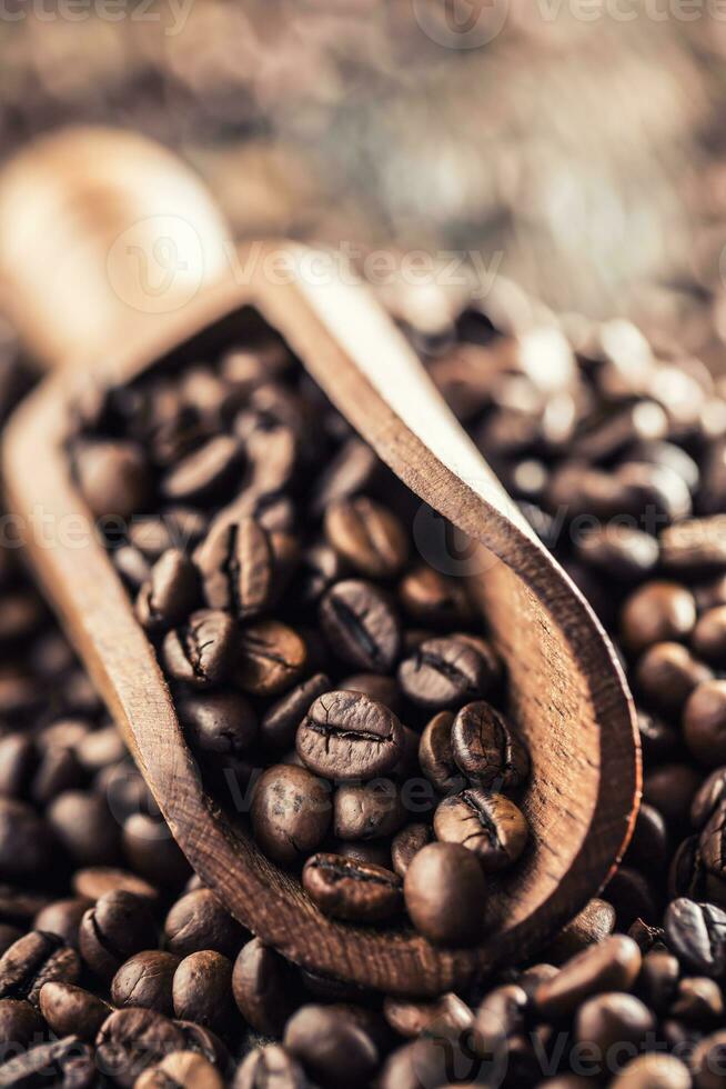 Wooden scoop full of coffee beans on old oak table photo