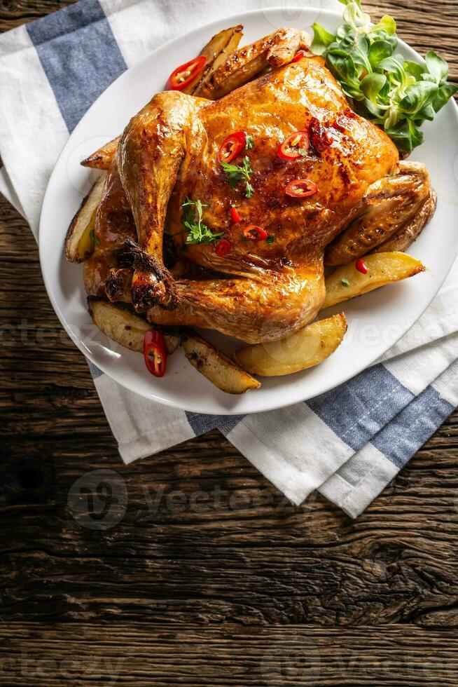 Roasted chicken and american potatoes with chili peppers and herbs - Top of view photo