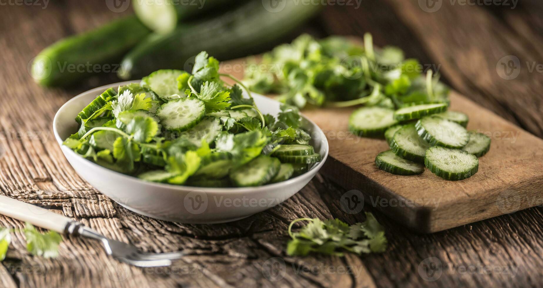 Sliced cucumber on a plate with parsley herb on rustic oak wood. photo