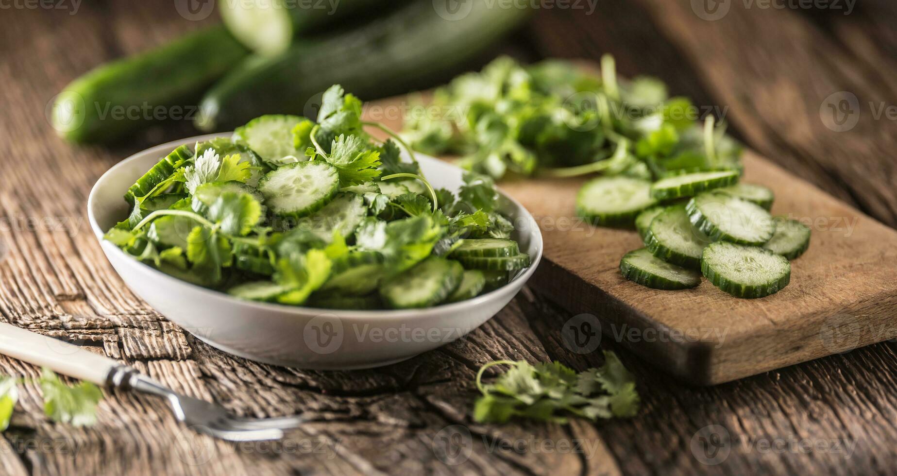 rebanado Pepino en un plato con perejil hierba en rústico roble madera. foto