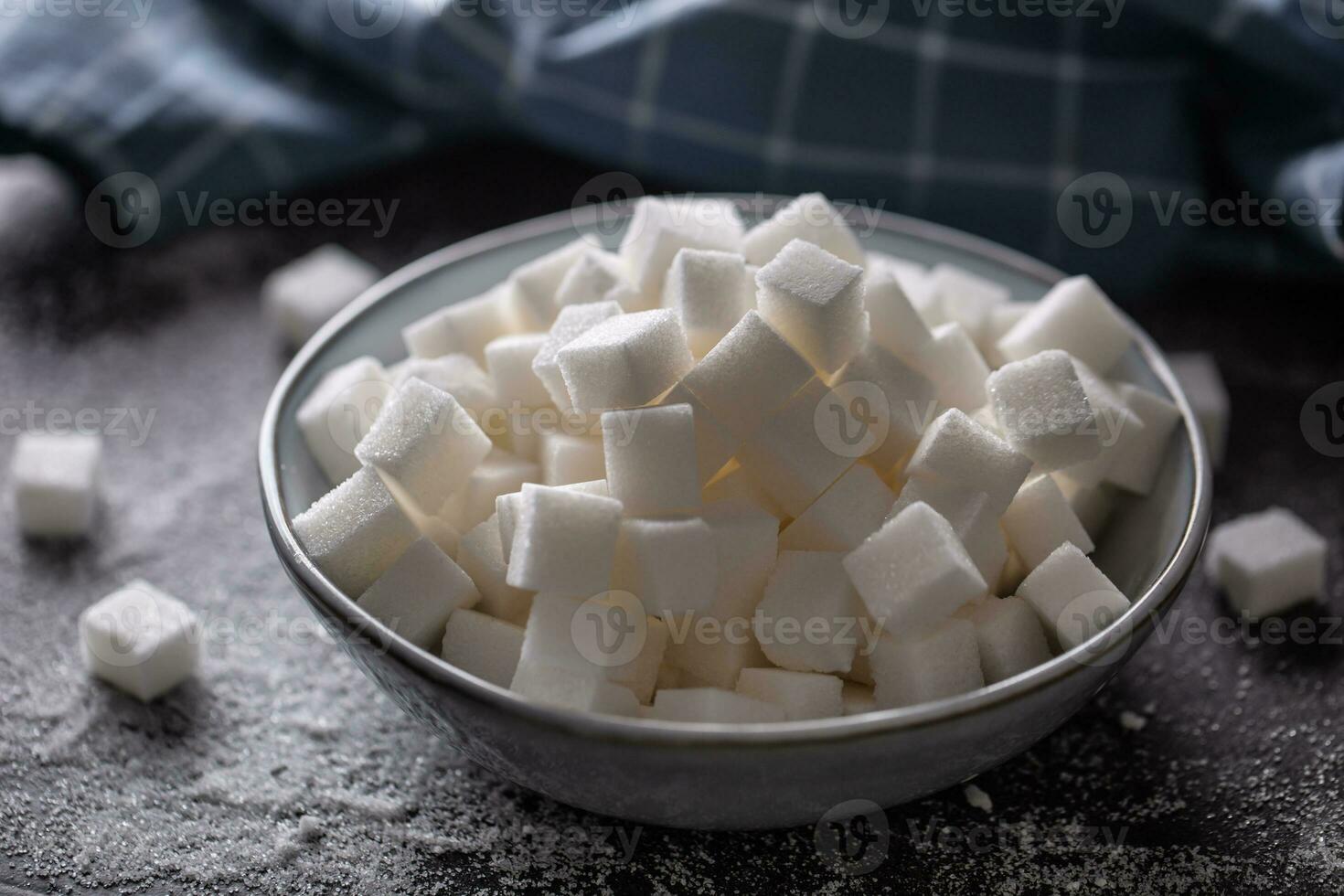 White sugar cubes in a blue bowl on the table photo