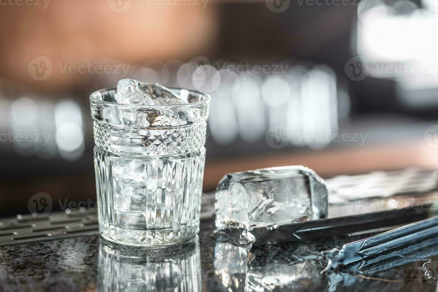 Ice cubes in glass at barcounter in night club or restaurant photo