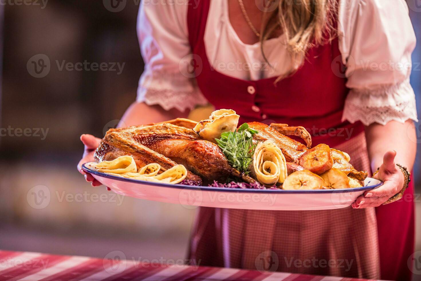 Woman holding garnished roasted duck in pub or restaurant photo
