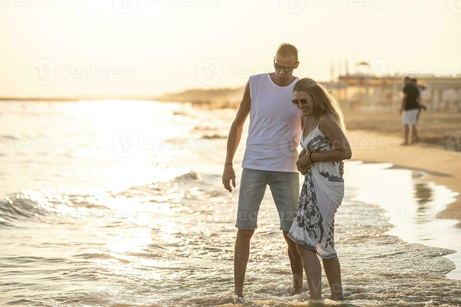 Happy middle-aged couple in love walking in the water on the beach at  sunset 27548644 Stock Photo at Vecteezy