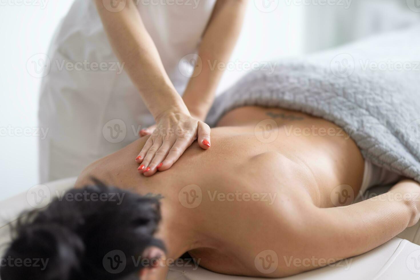 Detail of a masseuse providing a massage to a female client on her sholder blade photo