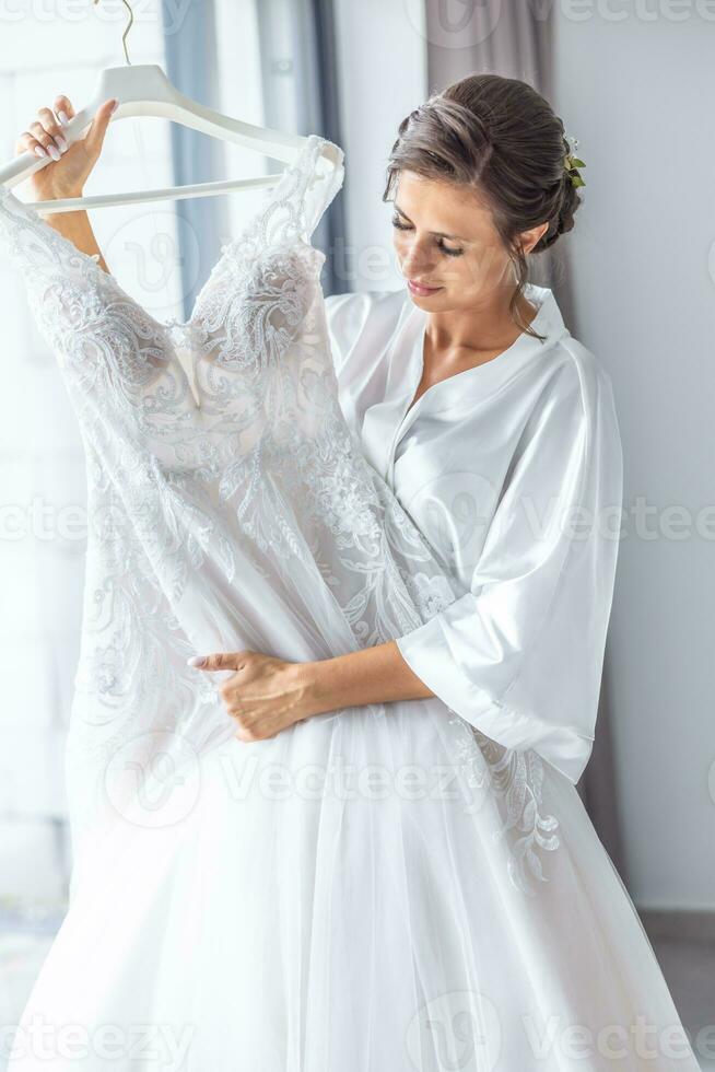 Bride looking at her wedding dress during ceremony preparation photo