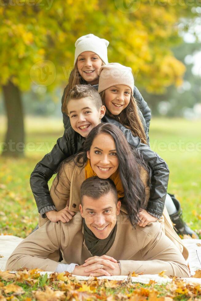 humano pirámide de cinco acostado miembros de el familia al aire libre en un otoño día foto