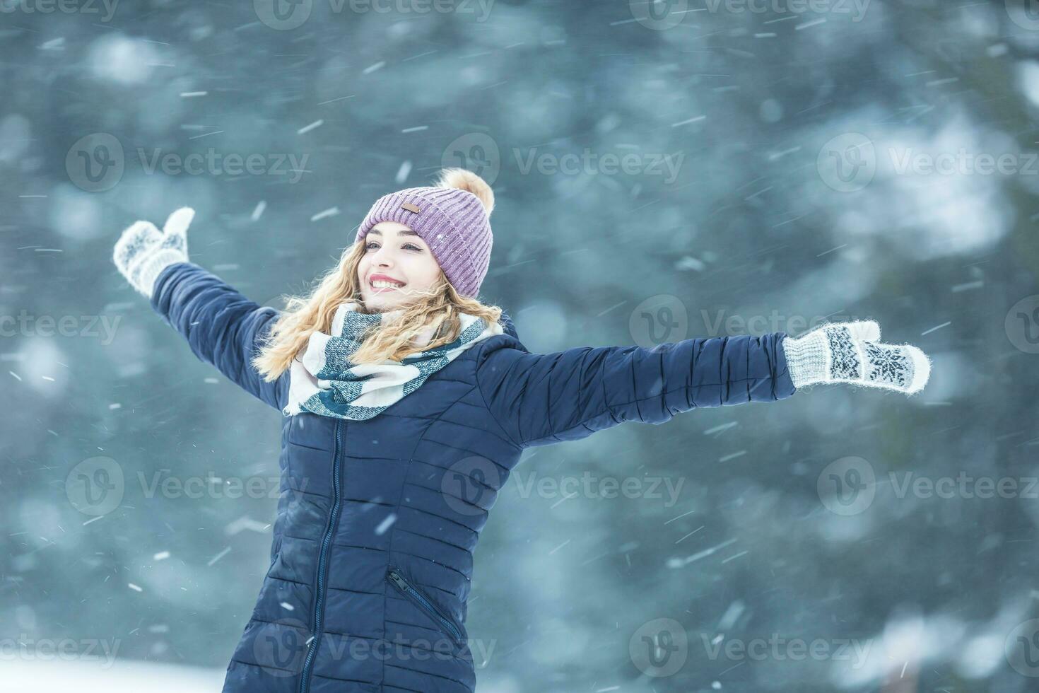 contento joven mujer en calentar ropa disfrutando invierno nevada foto