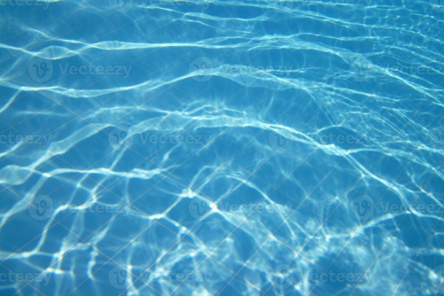 blue water with ripples onte surface. defocus blurred trasparent blue colored clear calm water surface texture. water waves with shinning pattern texture background. photo