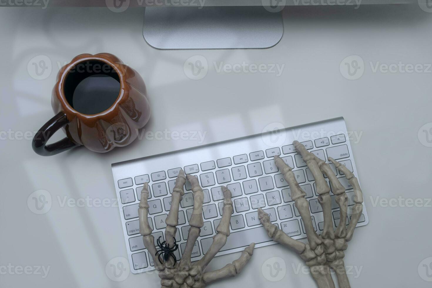 Skeleton hands on a computer keyboard witk spooky light photo