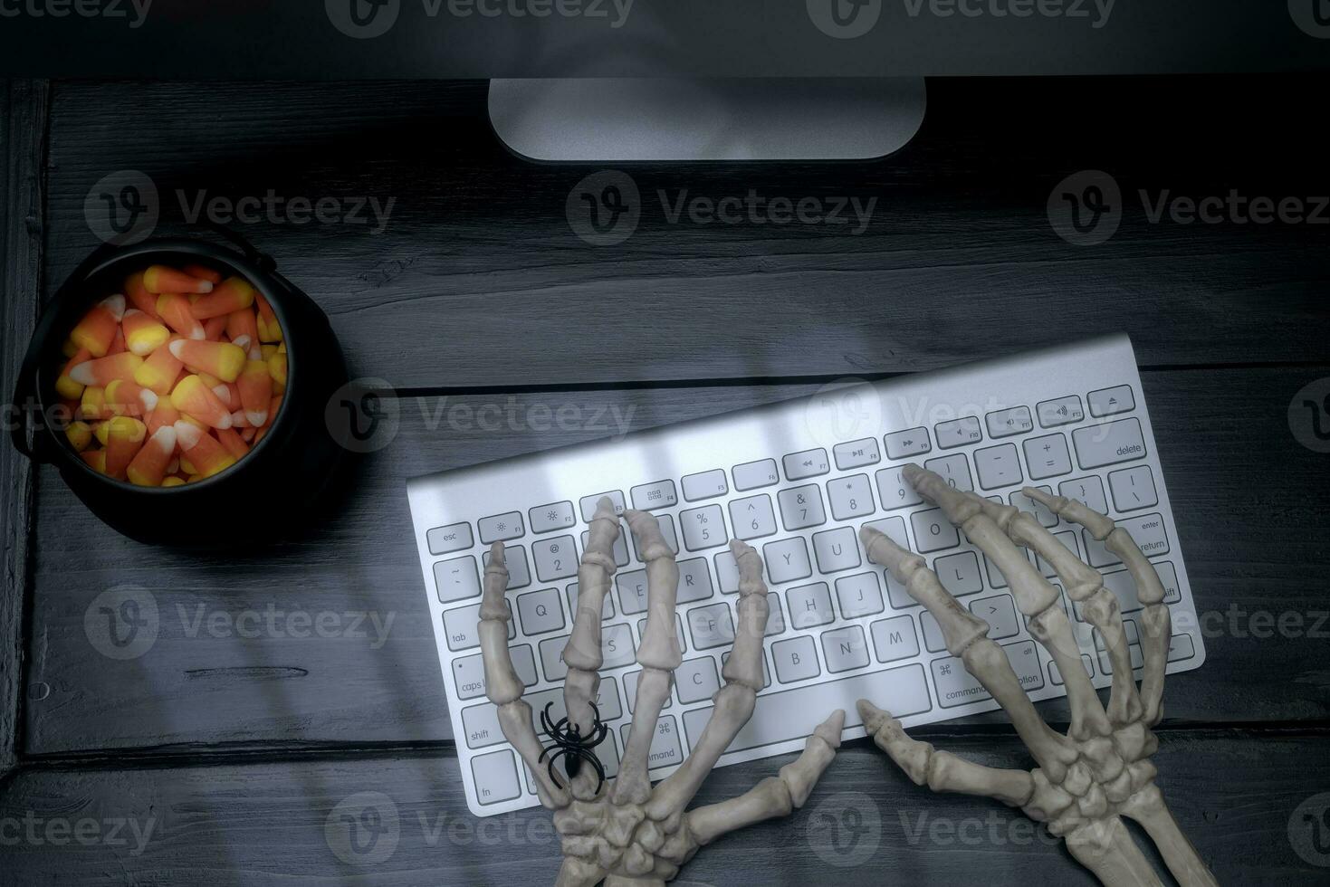 Skeleton Hands on a Keyboard on a Black Desk photo