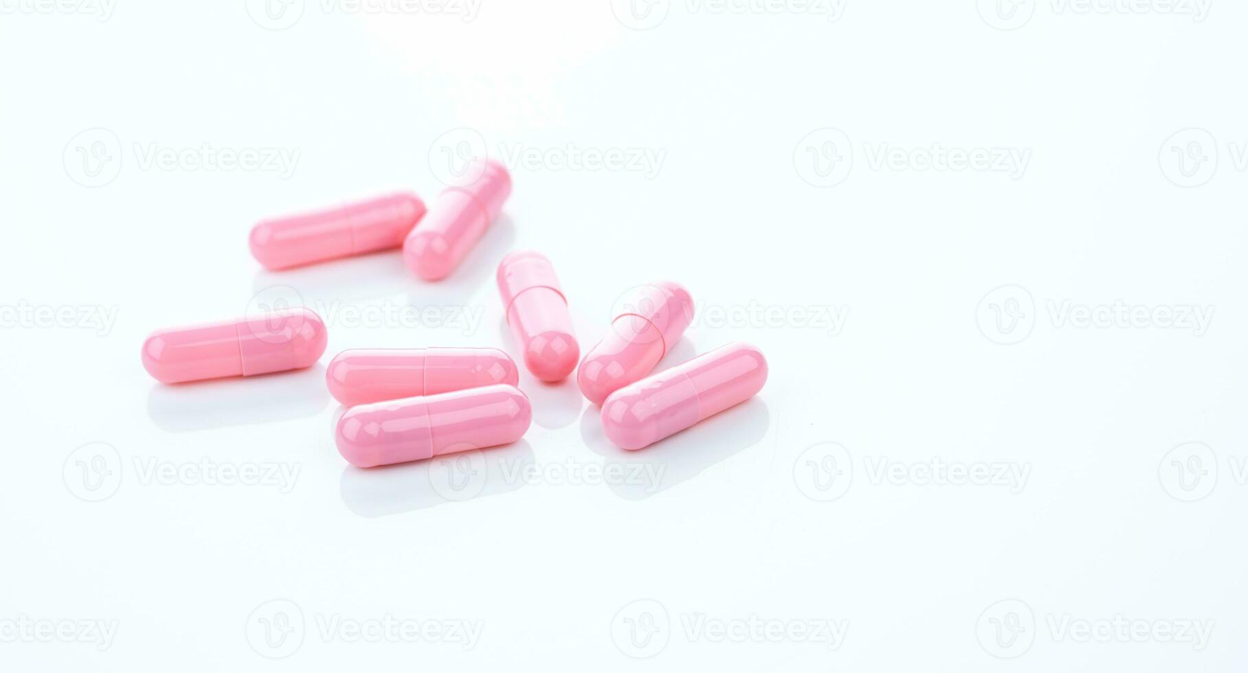 Pink capsule pills on white background. Pharmaceutical industry. Vitamins, minerals, and supplements concept. Pharmacy products. Pharmaceutical medicine. Prescription drugs. Healthcare and medicine. photo