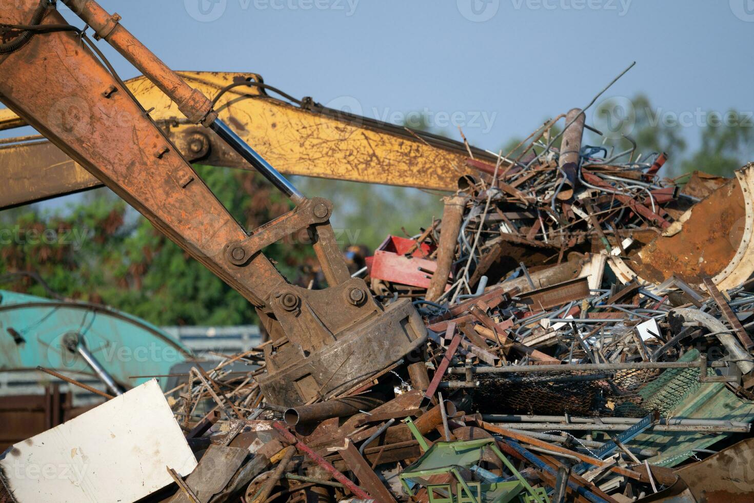 Excavator magnet lifting steel scraps from recycling materials pile at scrap yard in recycling factory. Excavator with electro and magnetic sucker magnet chuck. Special excavator. Scrap metal magnet. photo