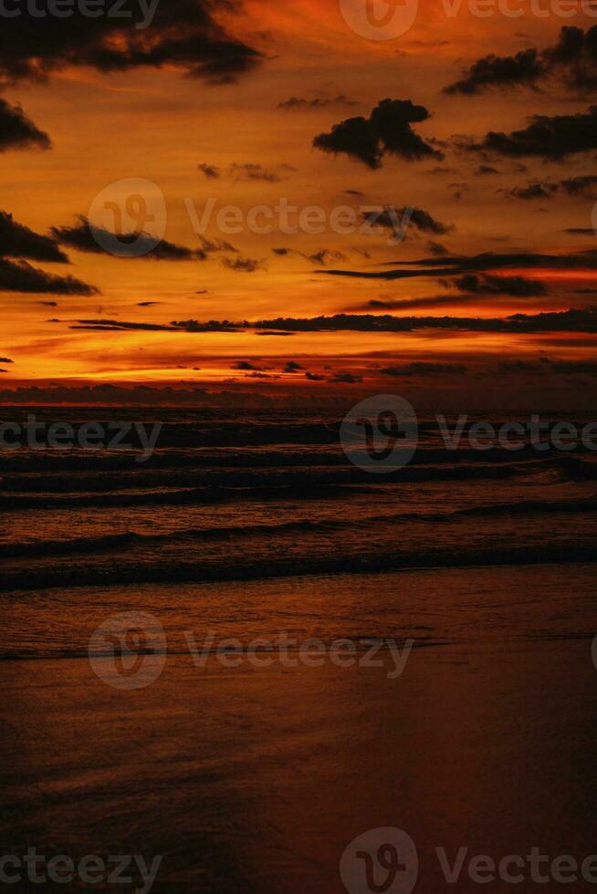 Amazing bright orange sunset on the Indian Ocean with waves on Bali island. Evening sunlight, fire sky photo