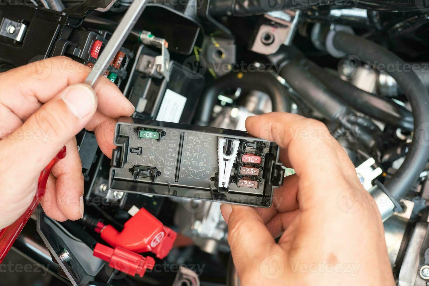 Mechanic holding Fuse box lid cover and Fuse Box Diagram or fuse specification chart on motorcycle,motorcycle maintenance and repair concept . selective focus photo