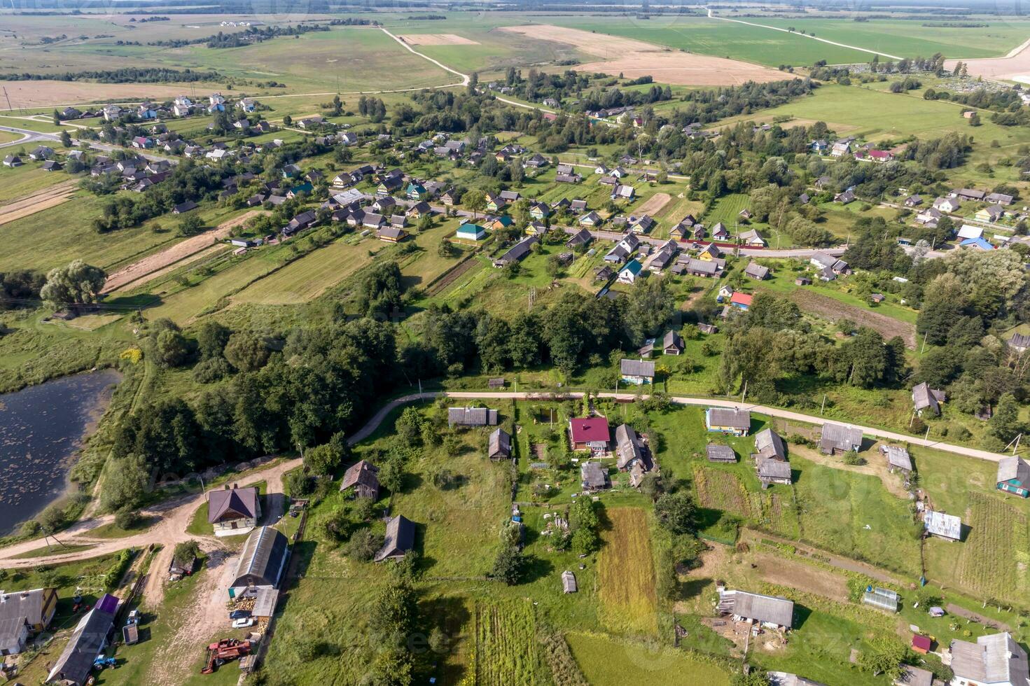 panoramic aerial view of eco village with wooden houses, gravel road, gardens and orchards photo