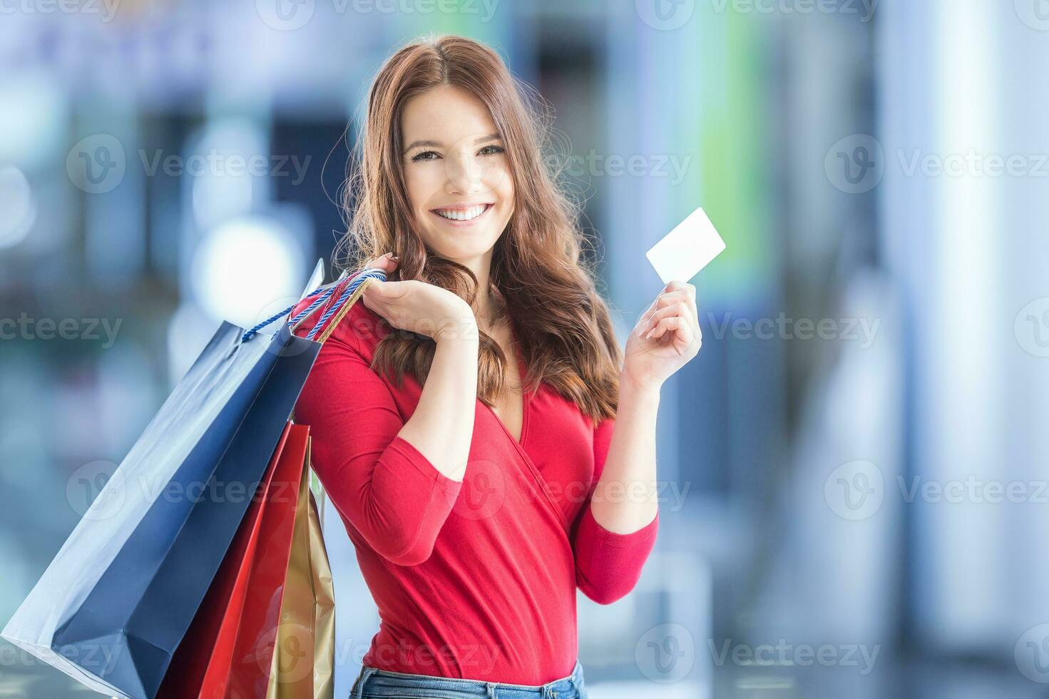 Beautiful happy girl with credit card and shopping bags in shopping mall. Shopping Center in the background. photo