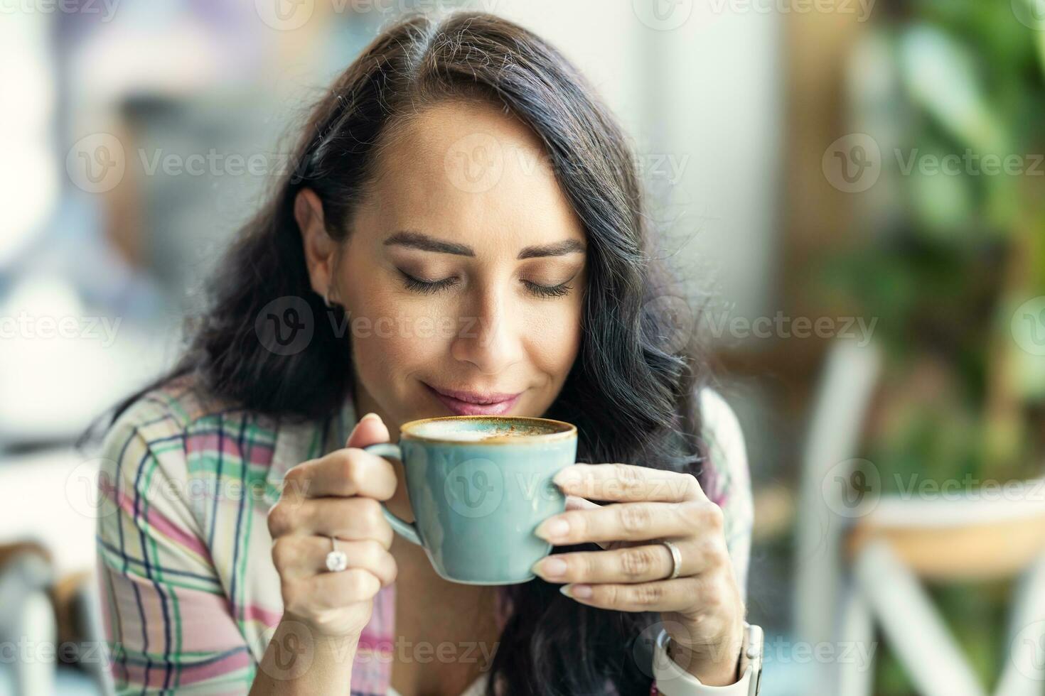 un morena disfruta el oler de recién elaborada café en un café foto