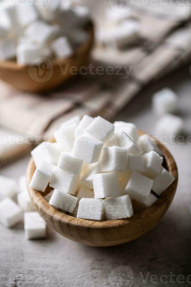 White sugar cubes in a wooden bowl on the table photo