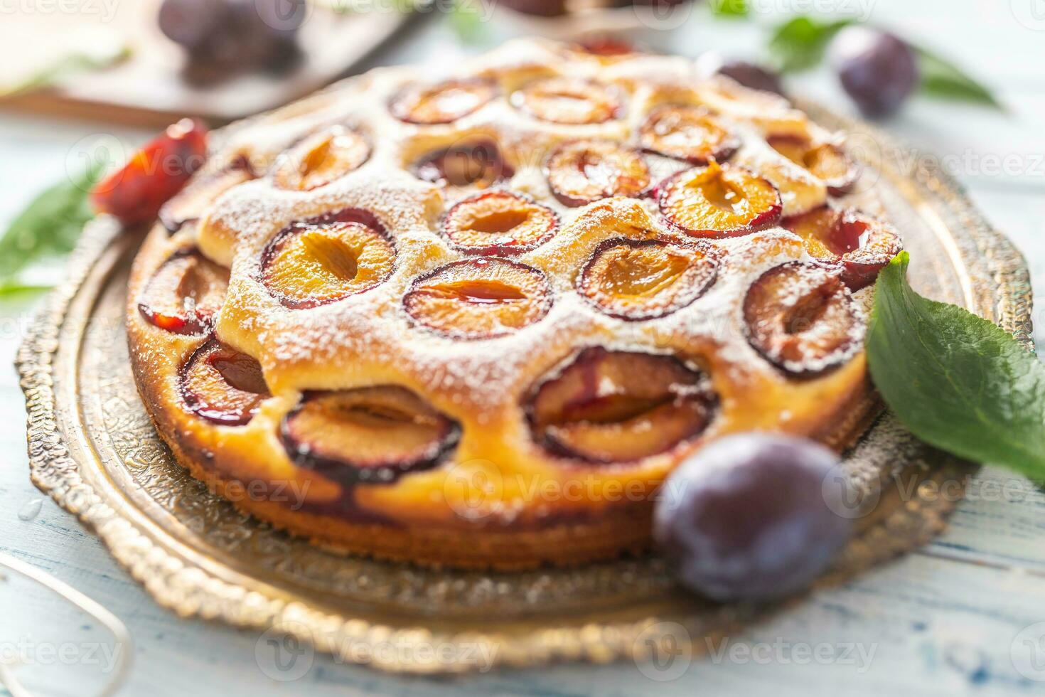 Homemade plum cake in vintage plate on wooden table. Plums pie with sugar powder photo