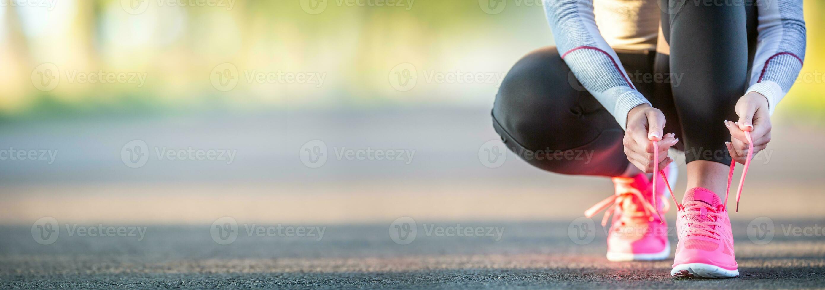 Woman runner tying shoelaces before jogging in autumn tree alley park. Sports female autumn outfit leggings and thermal underwear. photo