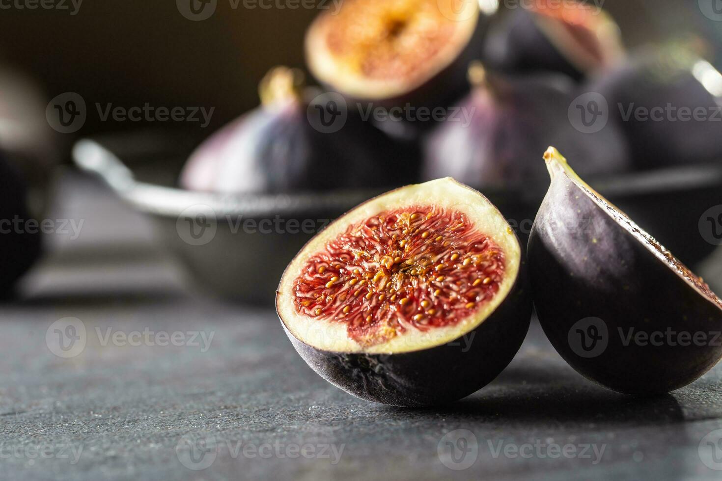 A few figs in a black bowl on an dark concrete table photo