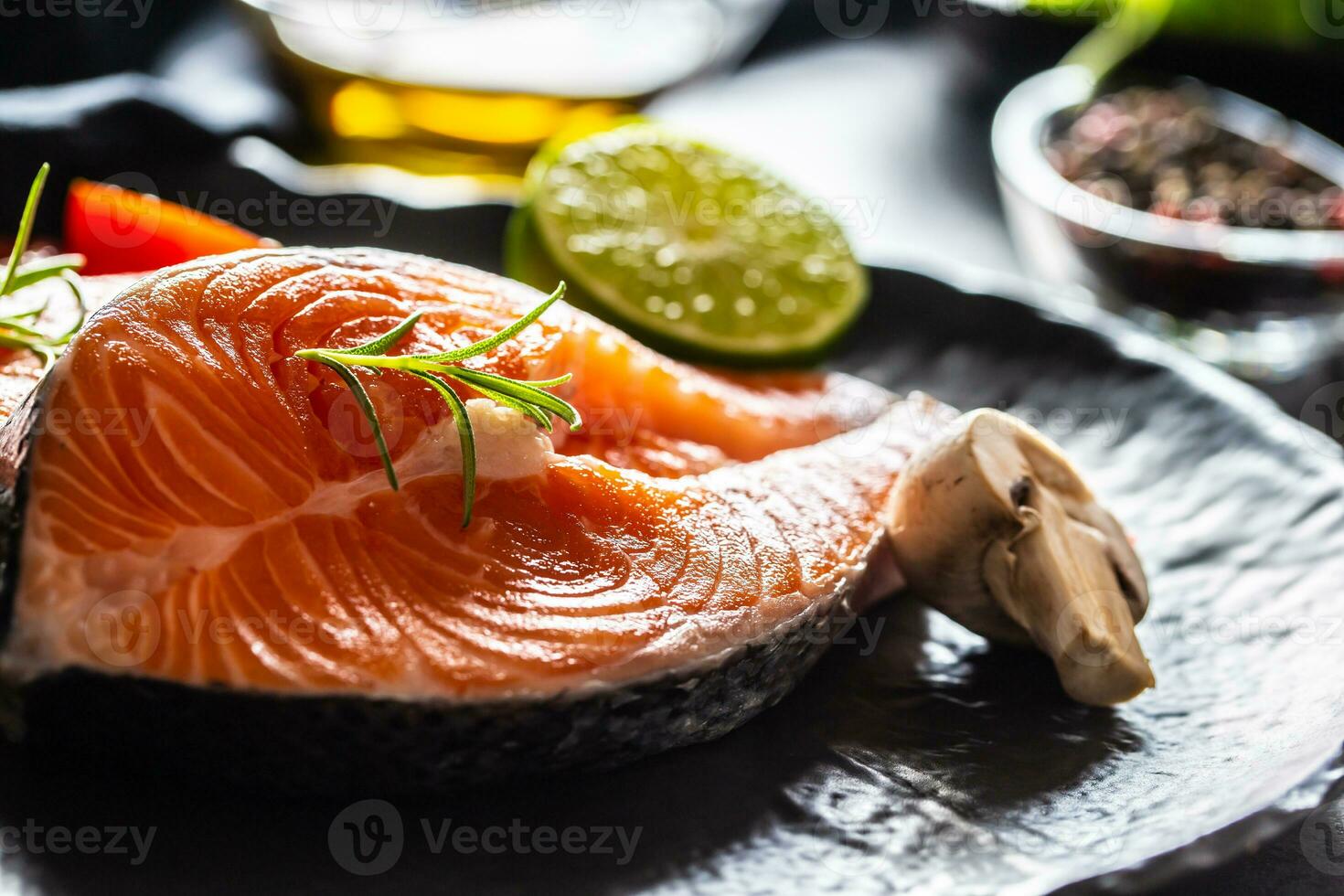 Salmon raw steaks rosemary tomatoes mushroom lime olive oil and spices - Close-up photo