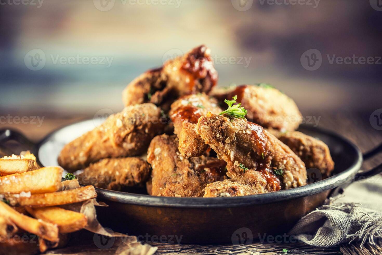 Fried chicken wings with fries on table in pub. photo