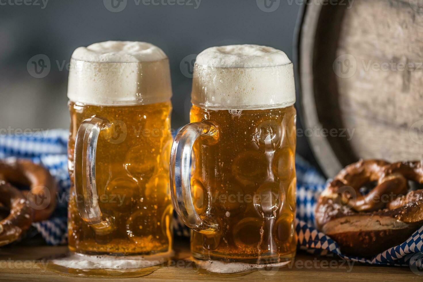 Oktoberfest two large beer with pretzel wooden barrel and blue tablecloth photo