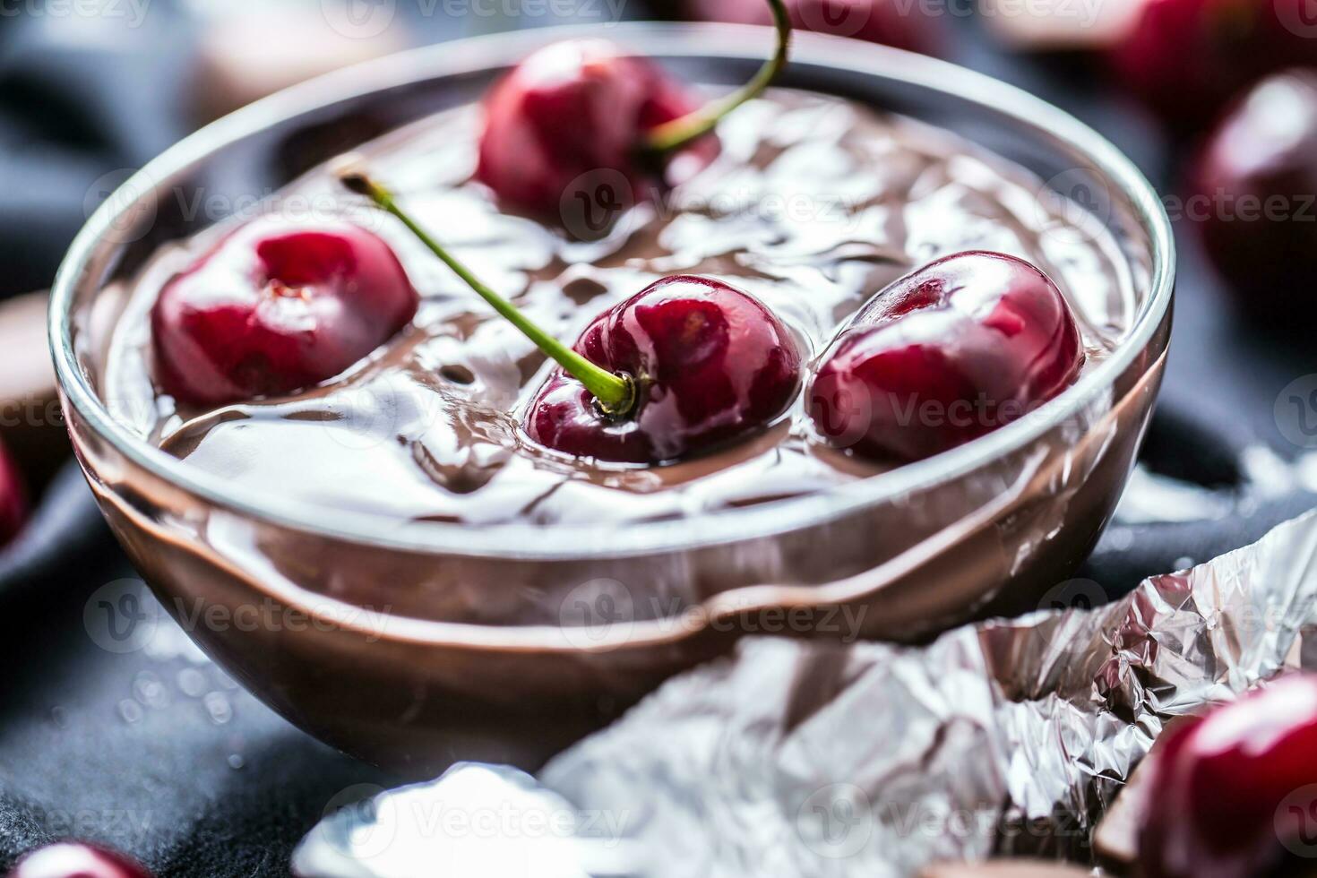 Fresh cherries in bowl with chocolate on dark tablecloth photo