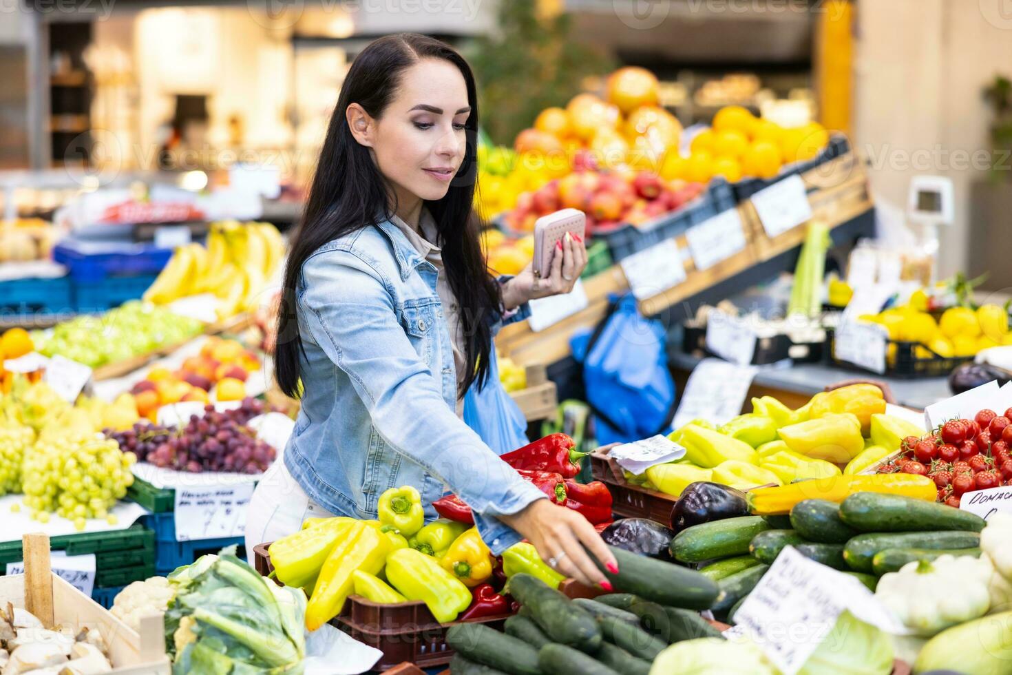 mujer compras en el afrmers' mercado alcanza fuera para un Pepino en el vegetales Departamento foto