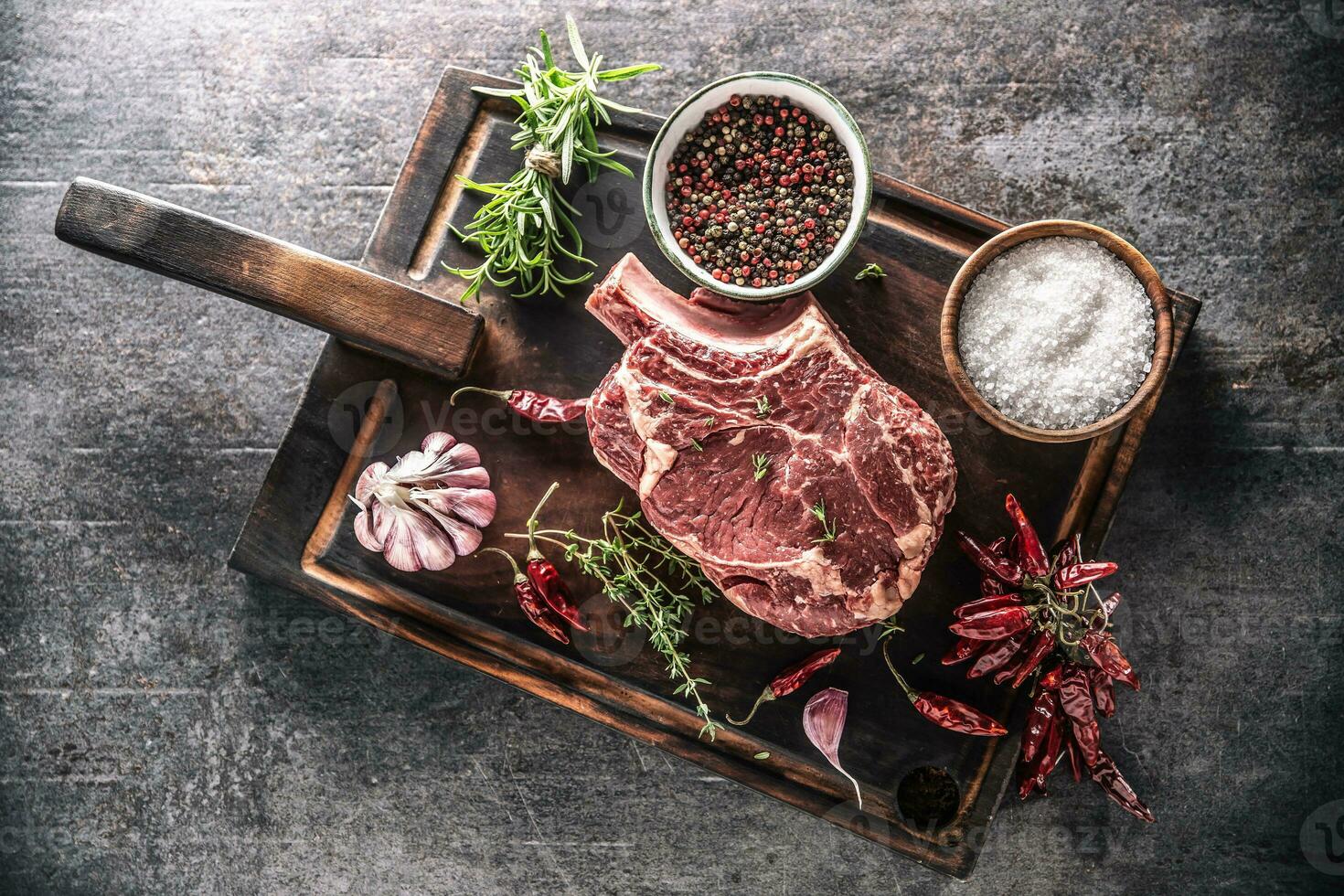 crudo carne de vaca filete en de madera corte tablero con sal especias chile pimientos tomillo y Romero foto