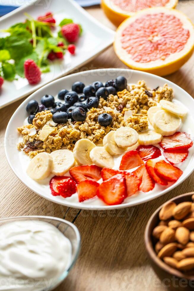 Healthy breakfast served with plate of yogurt muesli blueberries strawberries and banana. photo