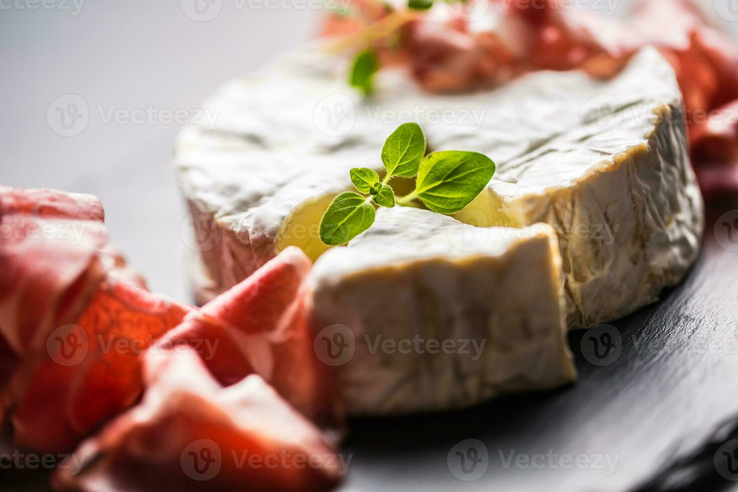 Cheese camambert from prosciutto and oregano herbs. photo