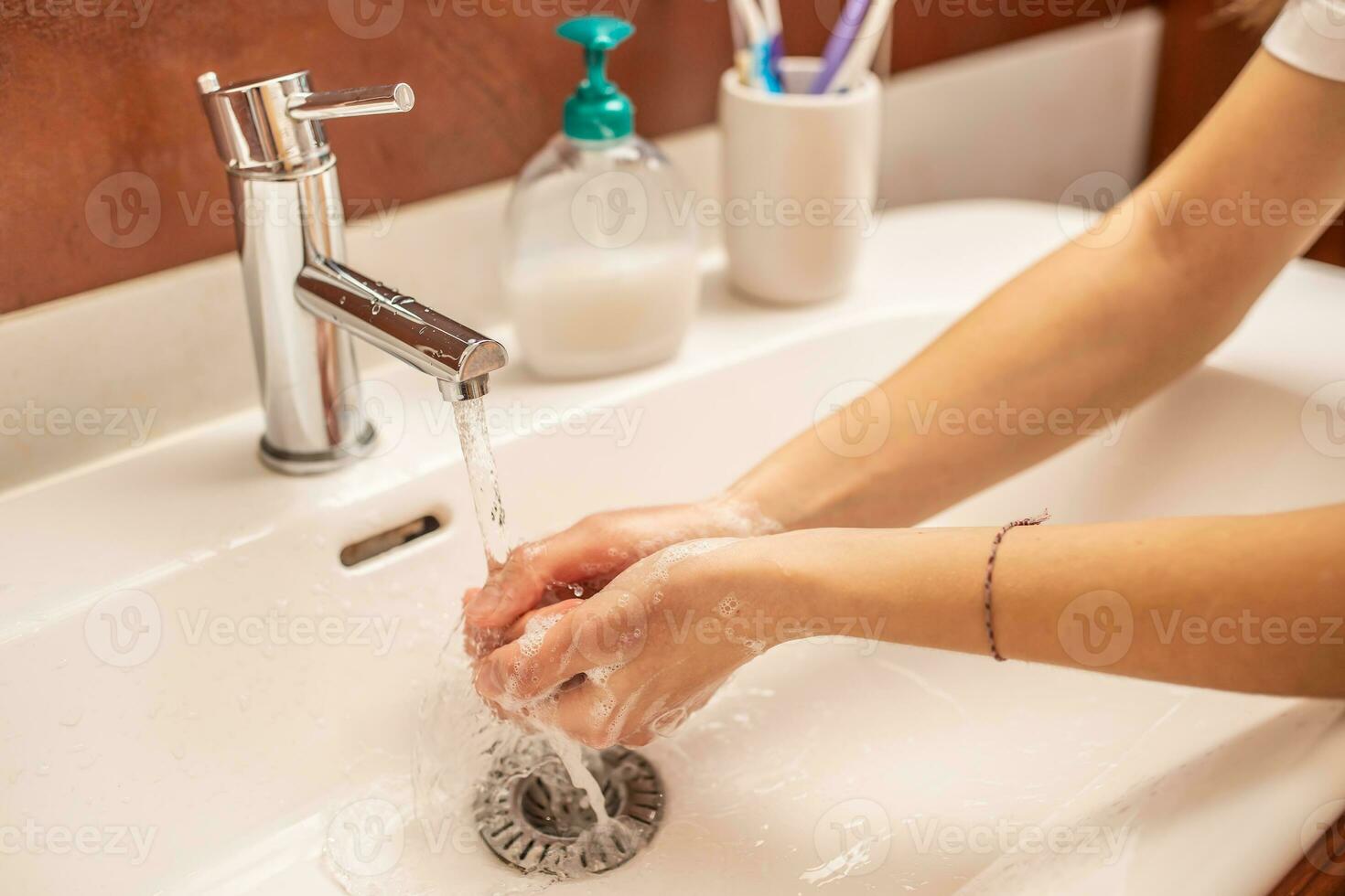 Lavado manos con agua y líquido jabón en el baño foto
