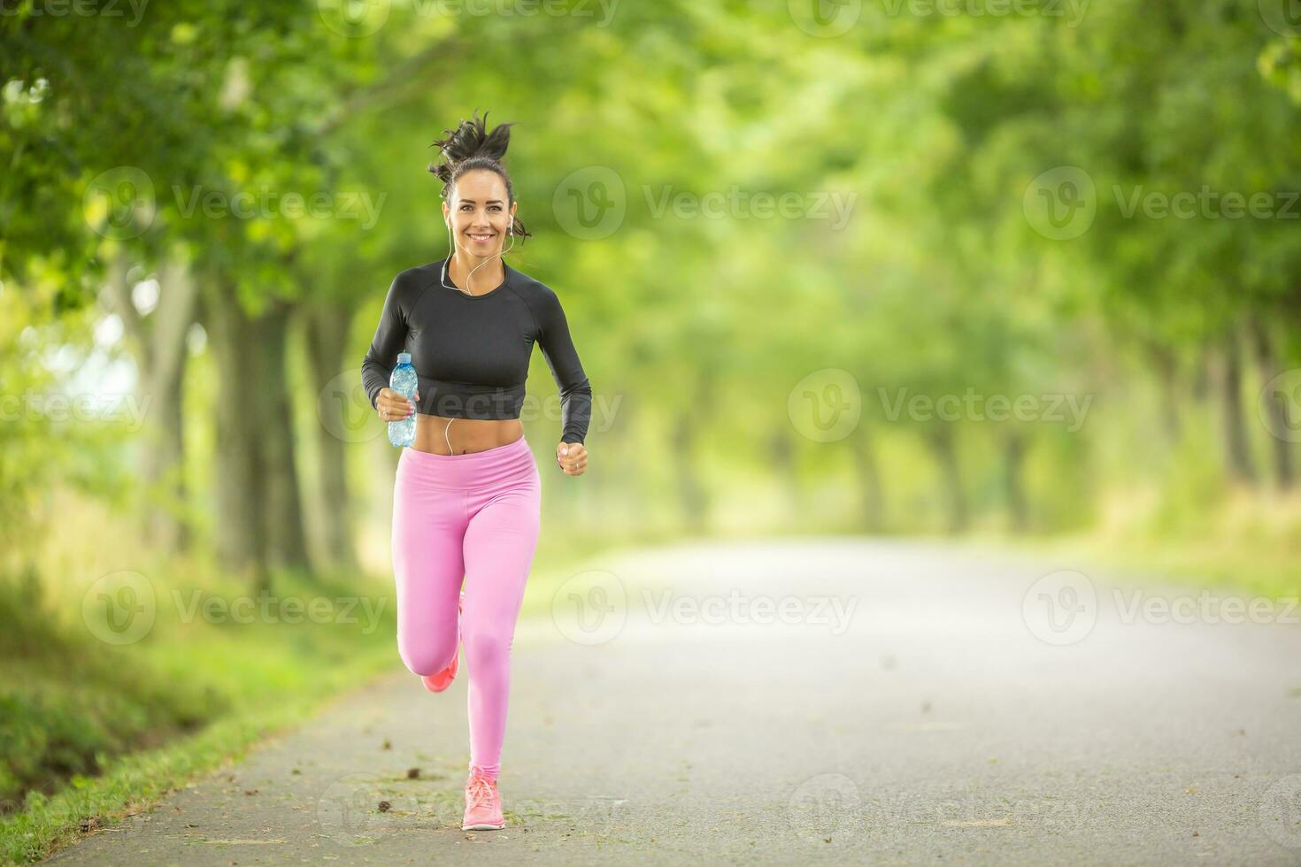Young woman runner running with a bottle of water. photo