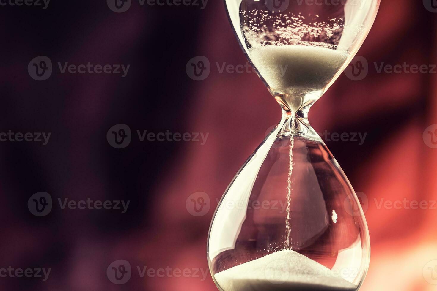 Modern hourglass in running time on wooden table photo