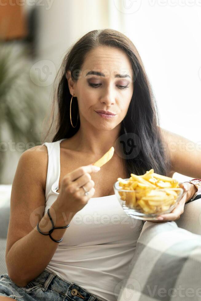 Woman hesitates about eating french fries due to unhealthy food effect of this diet photo