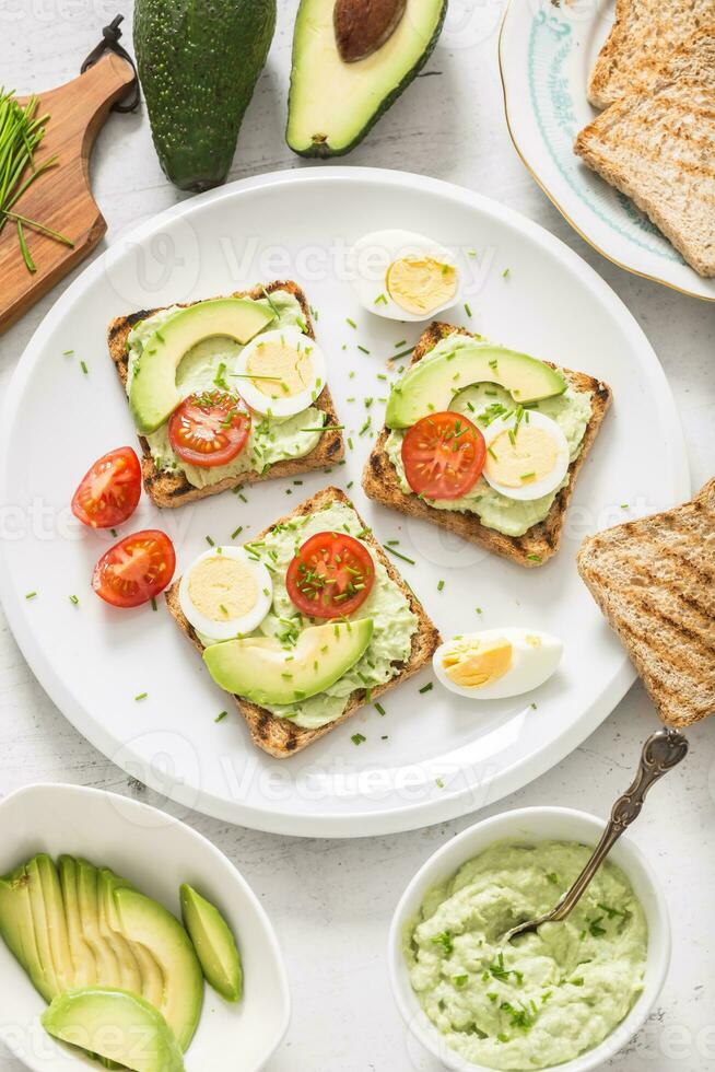 Healthy breakfast from toasts with avocado spread guacamole egg tomato and chives. photo