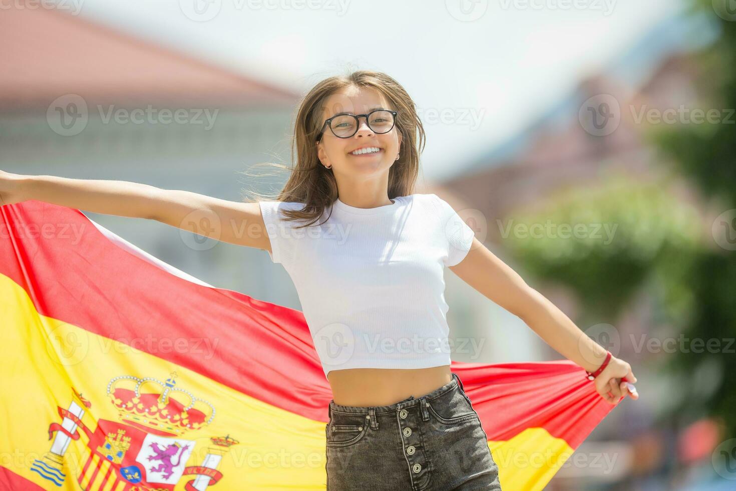 Happy girl tourist walking in the street with spanish flag photo