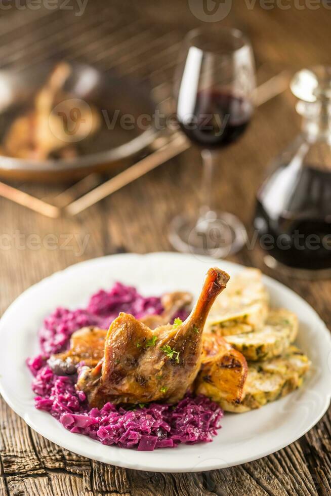 parte de asado Pato pierna rojo repollo hecho en casa empanadillas en plato y rojo vino en el antecedentes foto