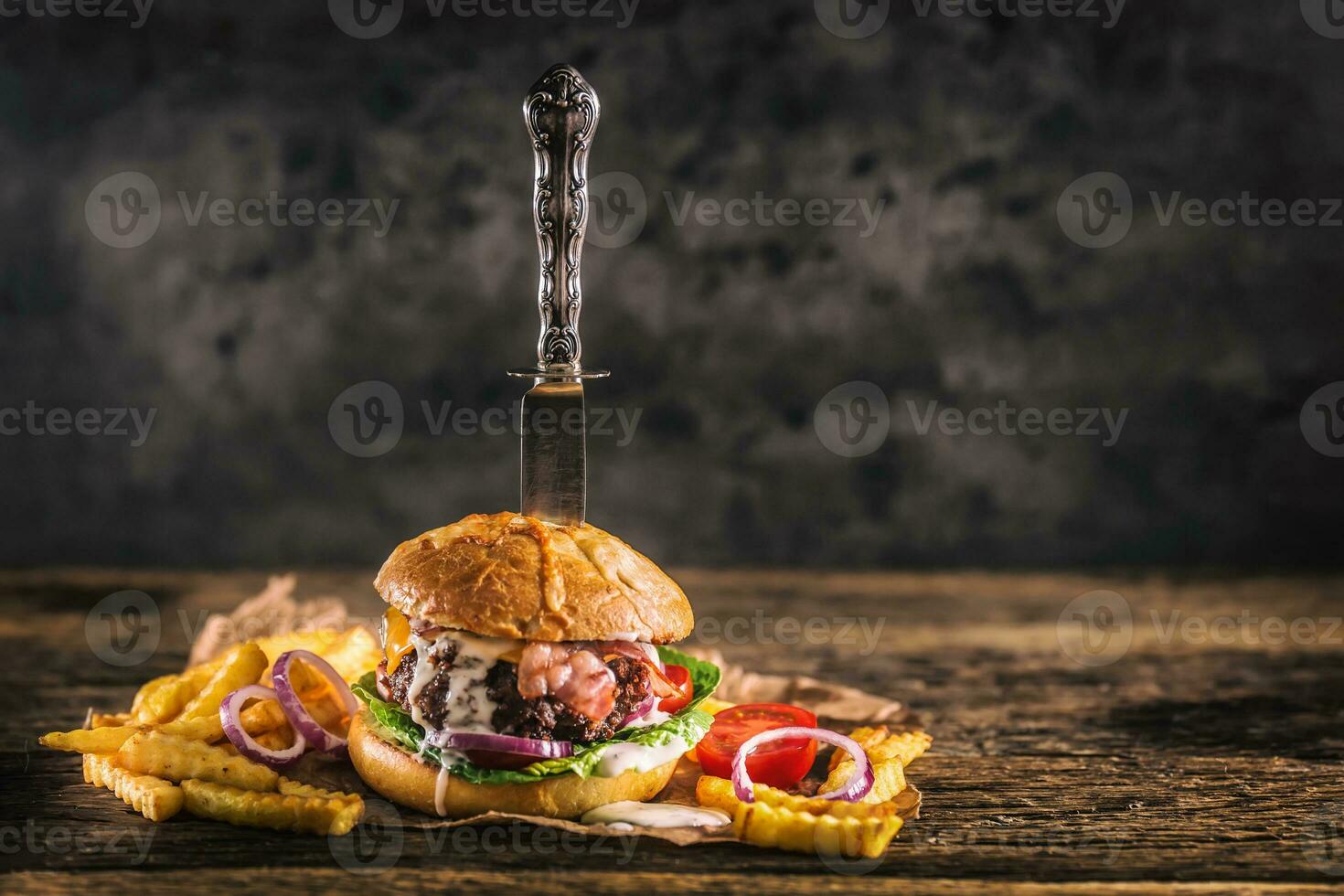 Close-up home made beef burger with knife and fries on wooden table photo