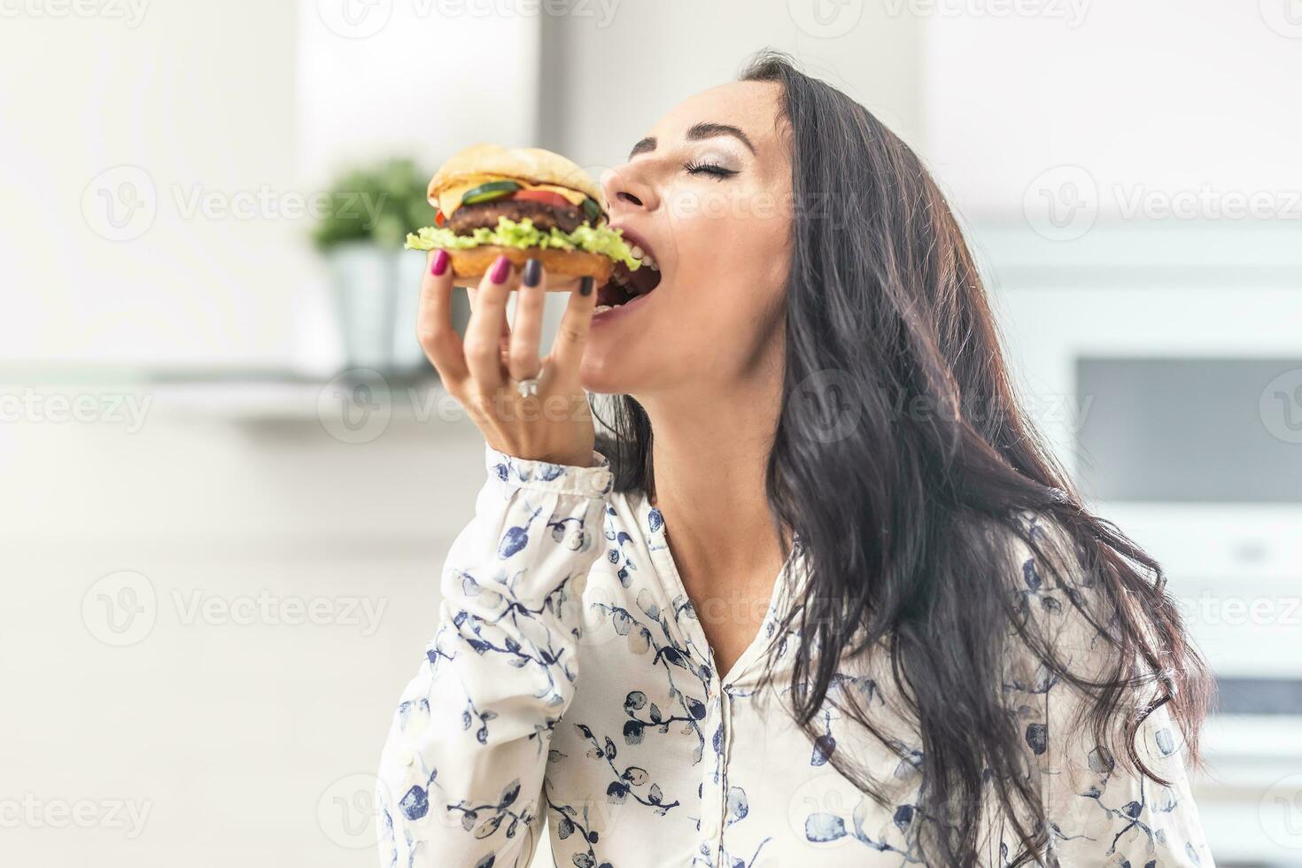 Enjoying a bite of a hamburger by a female photo